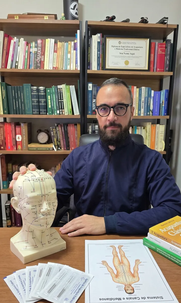 Diego Rodrigues, acupunturista da TianXiang, no consultório com um modelo de cabeça com os pontos de acupuntura